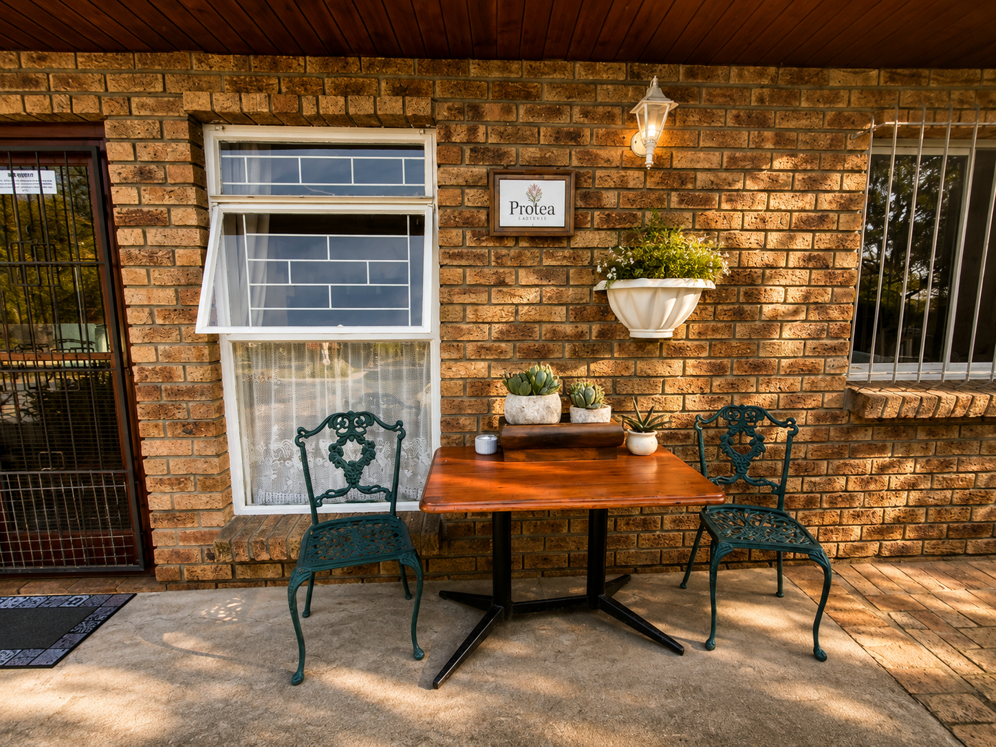 Private patio entrance to the Protea Suite with outdoor table, chairs and warm brick exterior in Durbanville